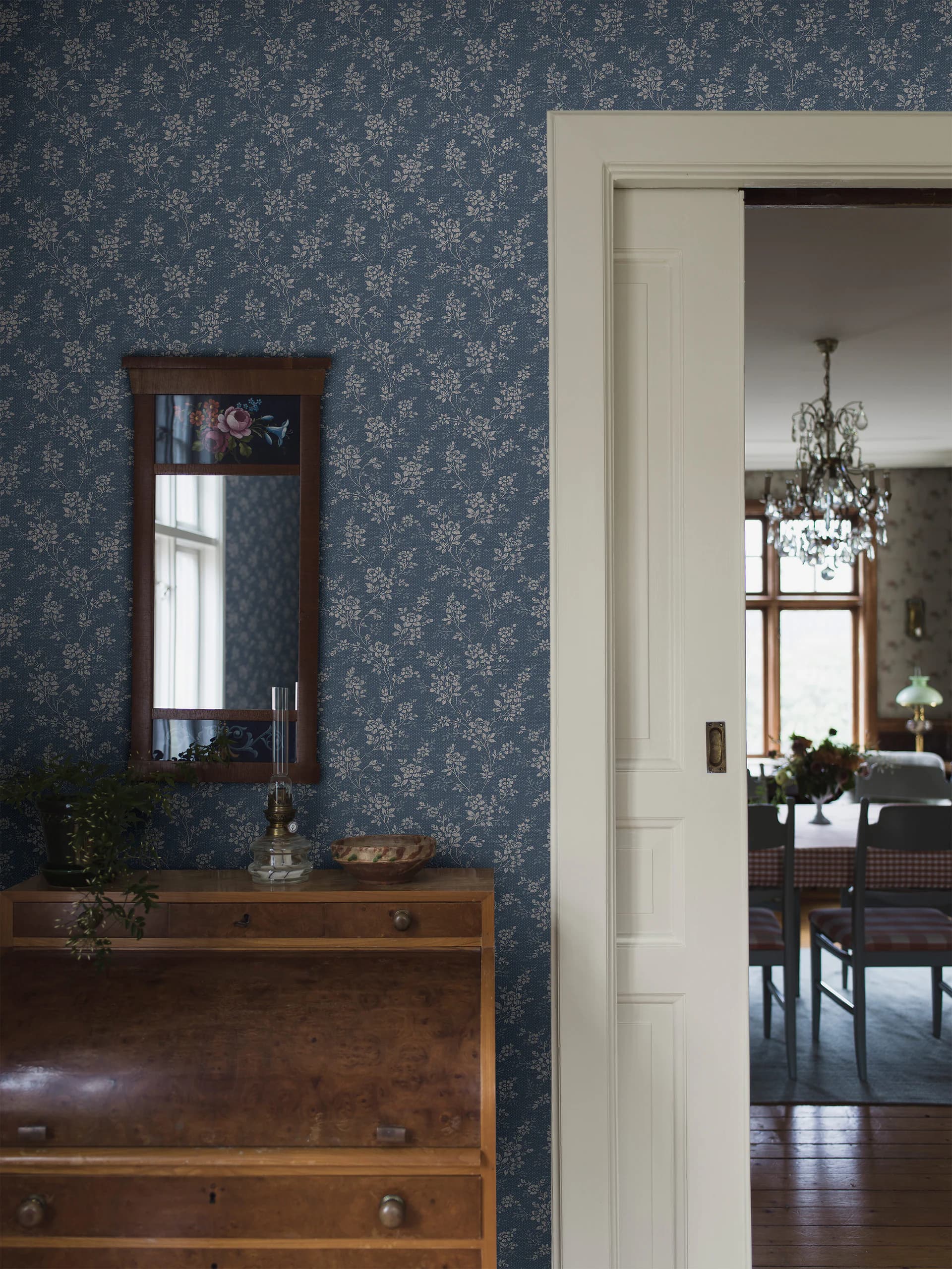 Hal met donkerblauw bloemetjesbehang, commode en spiegel
