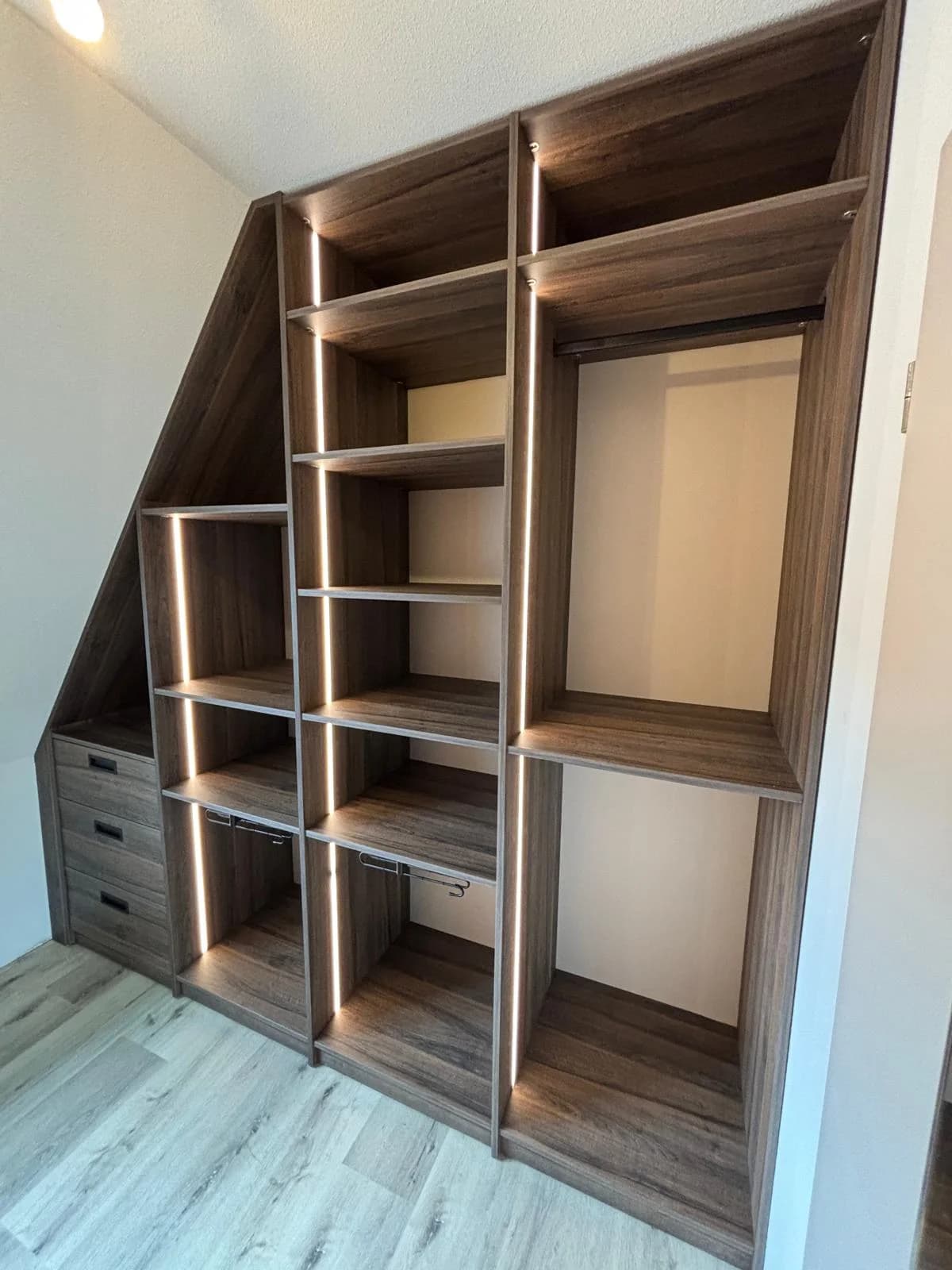 Open kast op maat in eikenlook langs een schuine wand, met ledverlichting