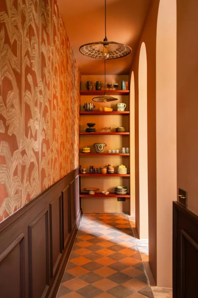 Gang met boogdoorgang en terracotta behang van Arte met palmbladeren