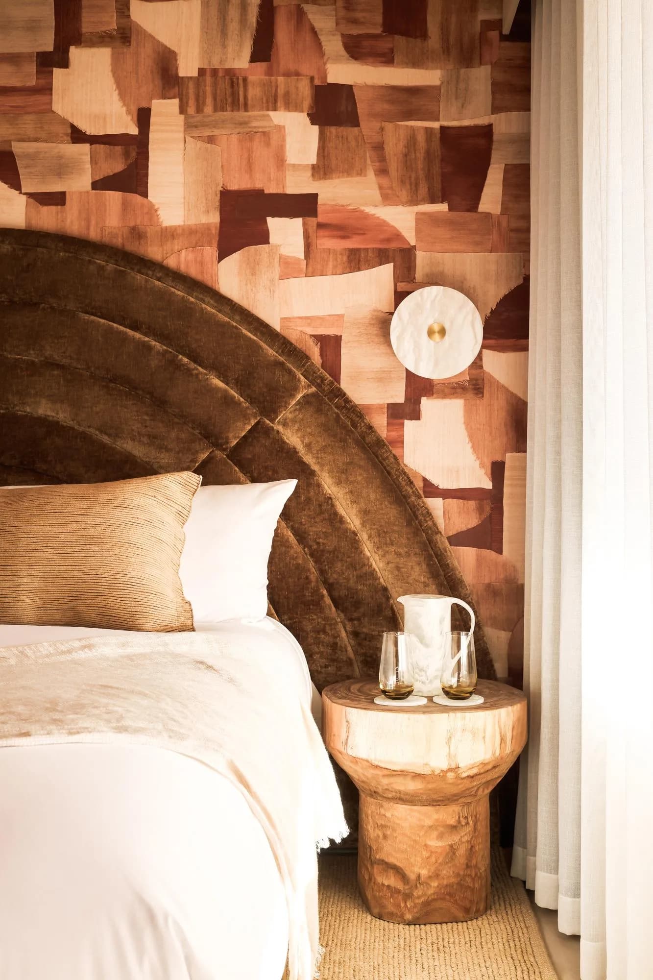 Hotelkamer met een halfrond hoofdbord voor Arte-behang in warme tinten