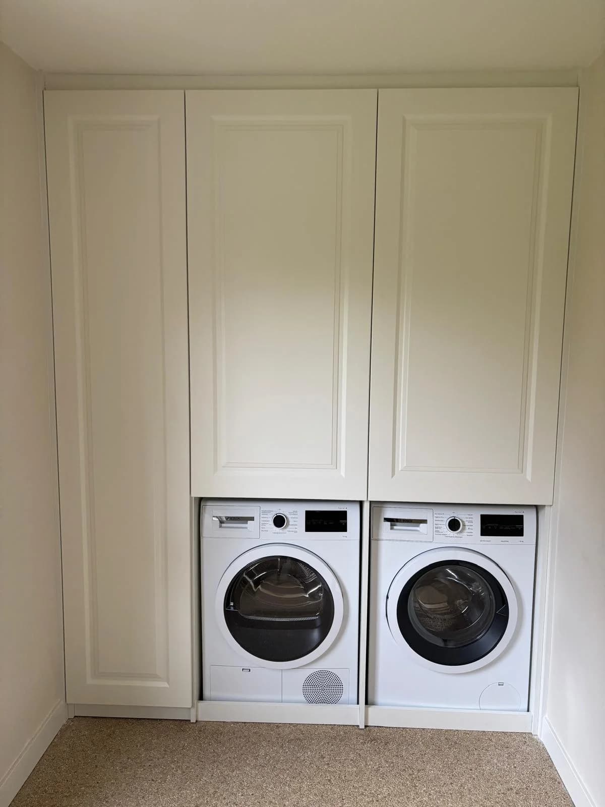 Witte kast op maat met wasmachine en droger onder hoge paneeldeuren
