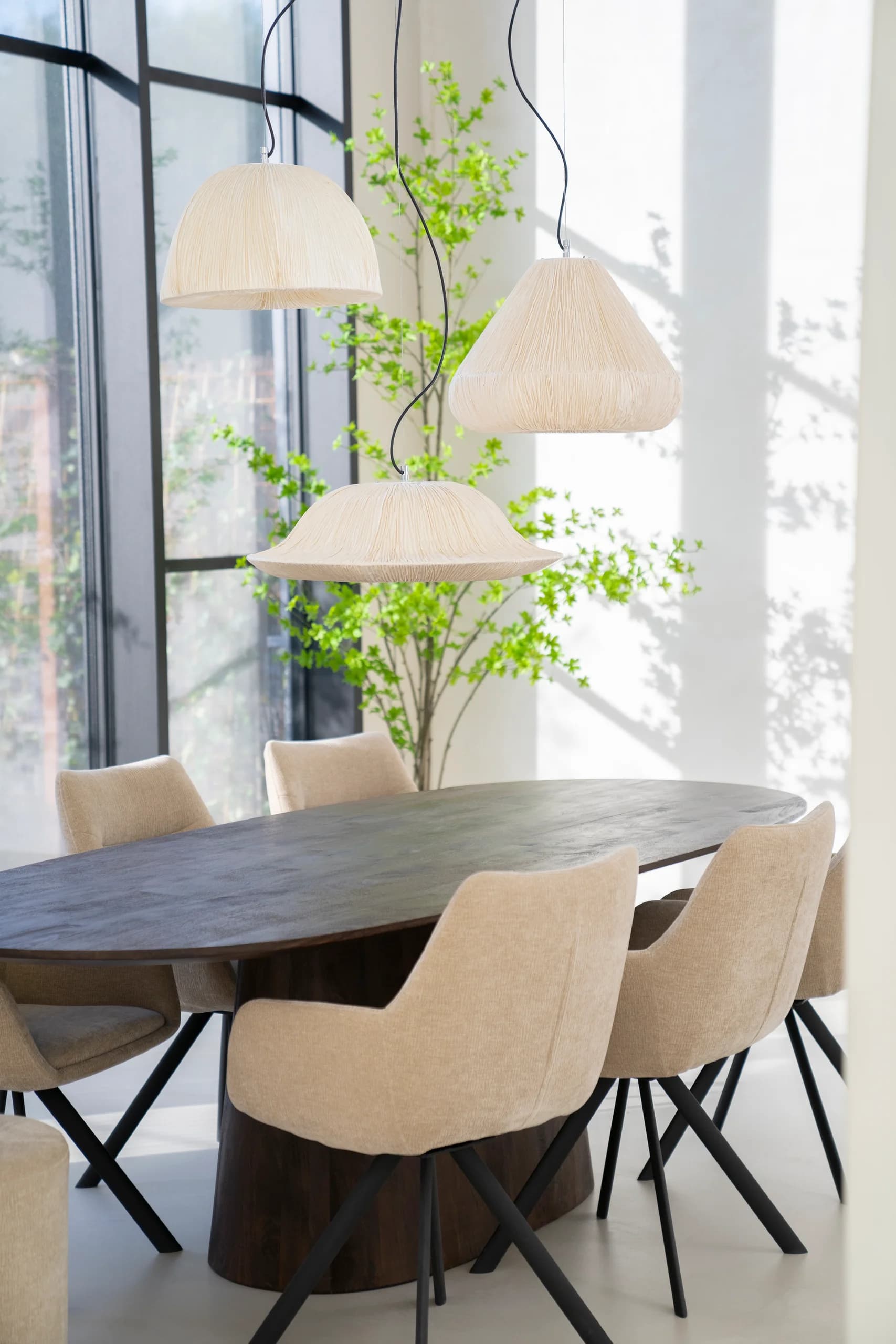 Eetkamer met ovale houten tafel, beige stoelen en drie hanglampen