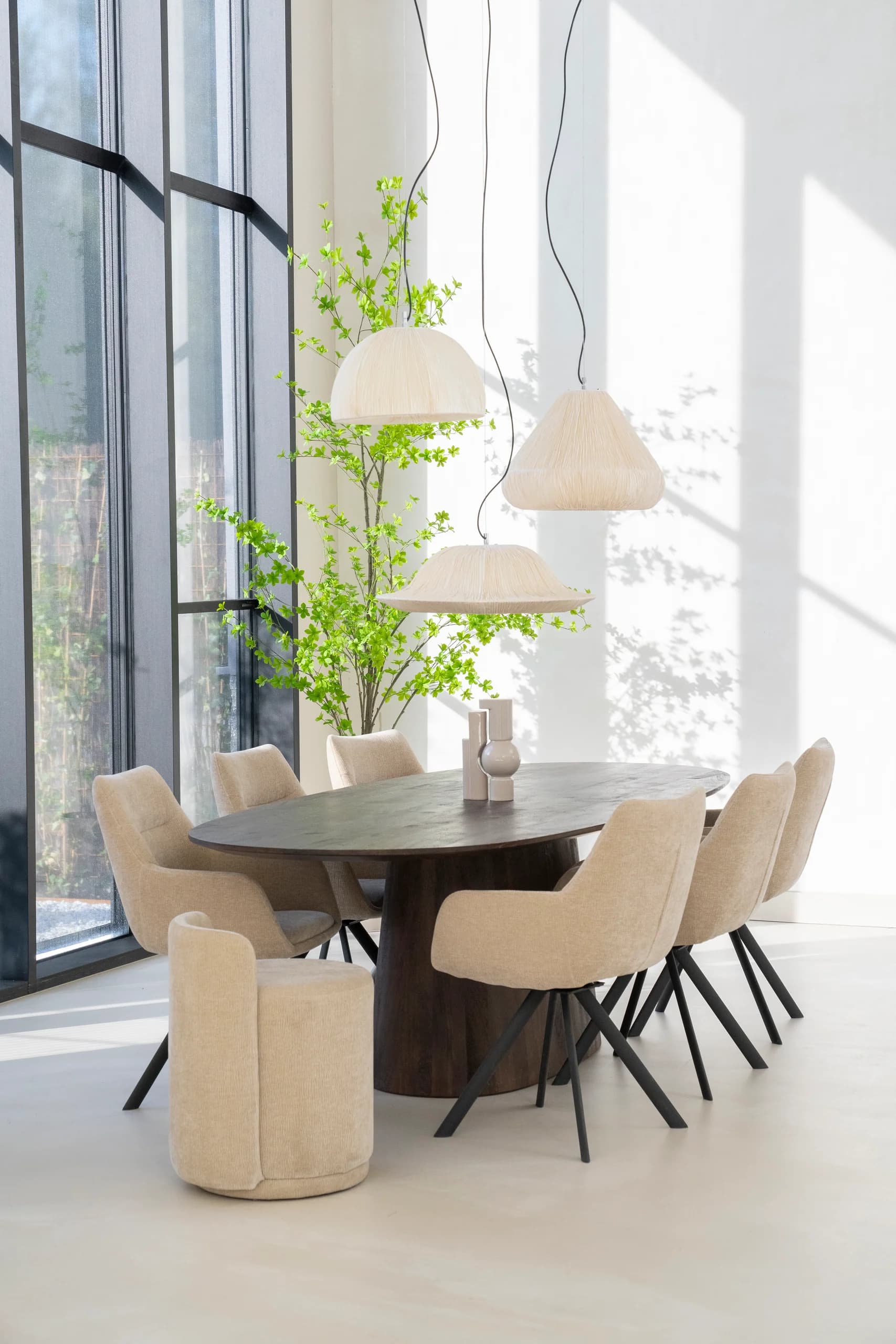 Eetkamer met donkere tafel, beige stoelen en grote ramen