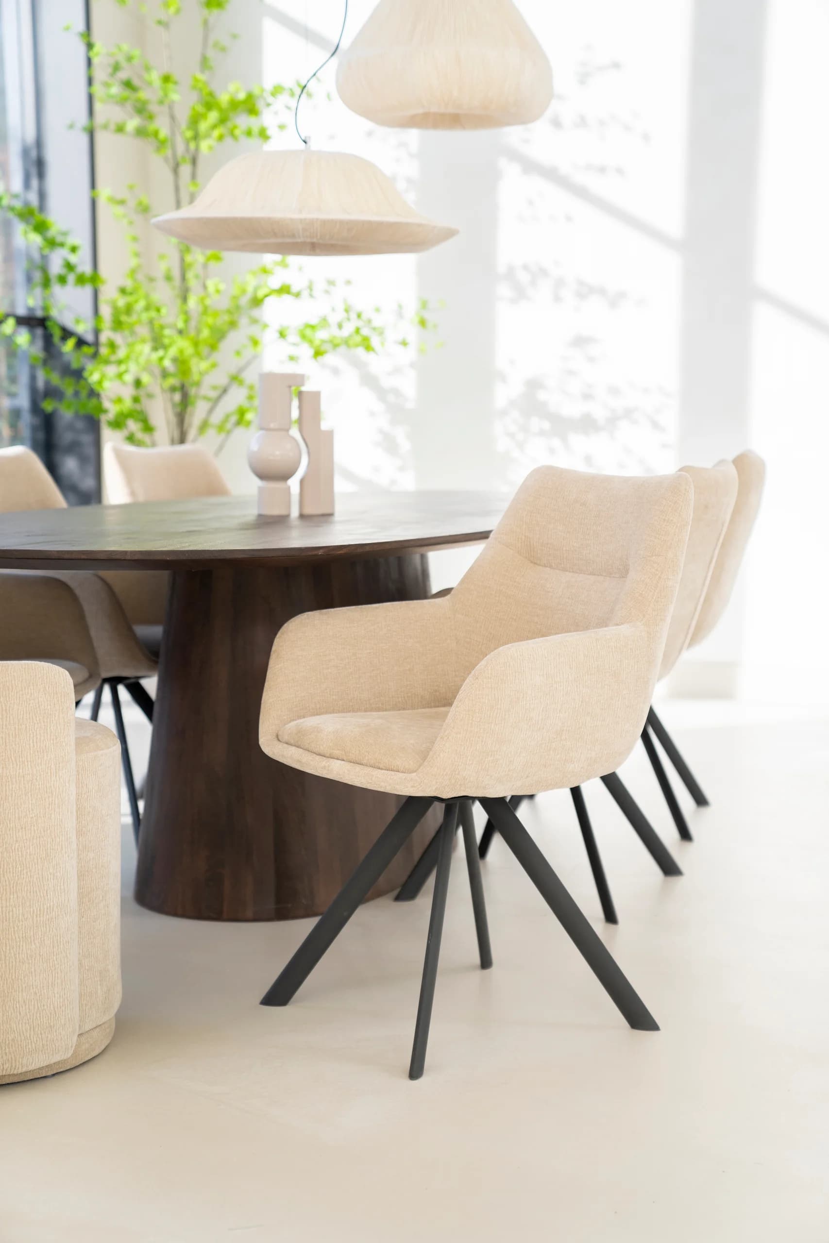 Beige draaistoelen aan een ovale donkere eettafel