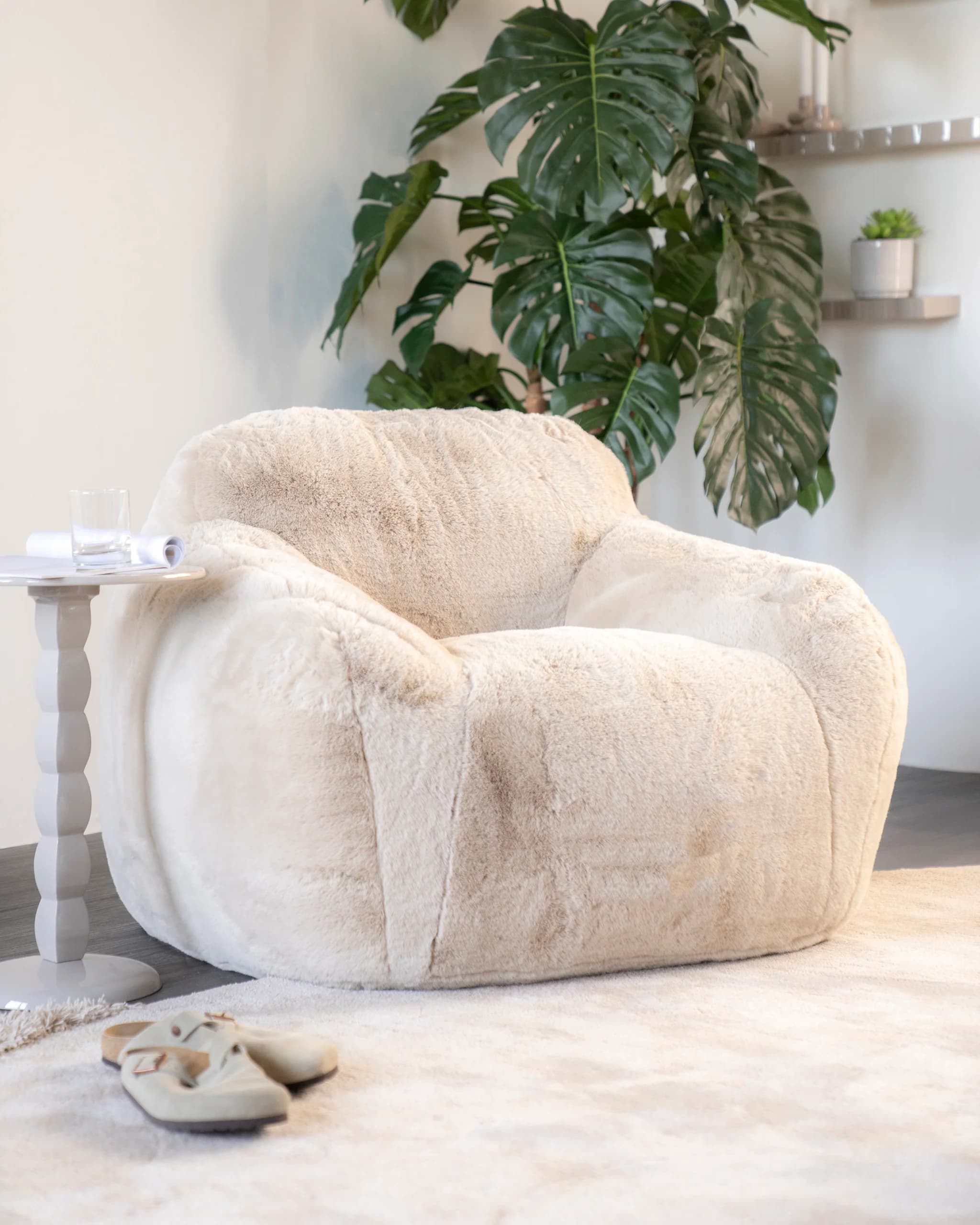 Zachte crèmekleurige teddy fauteuil bij een plant