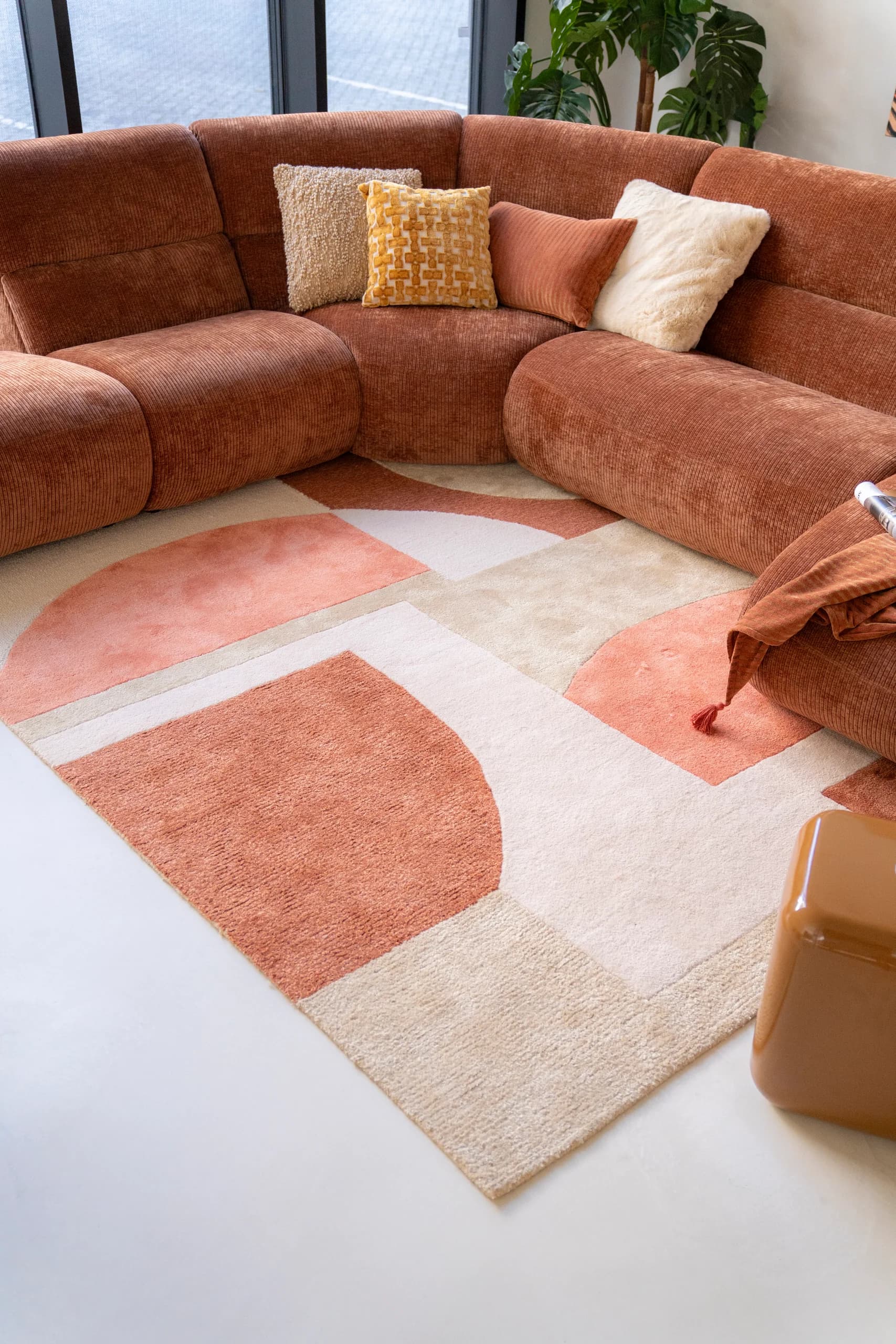 Terracotta hoekbank met kussens op een grafisch vloerkleed
