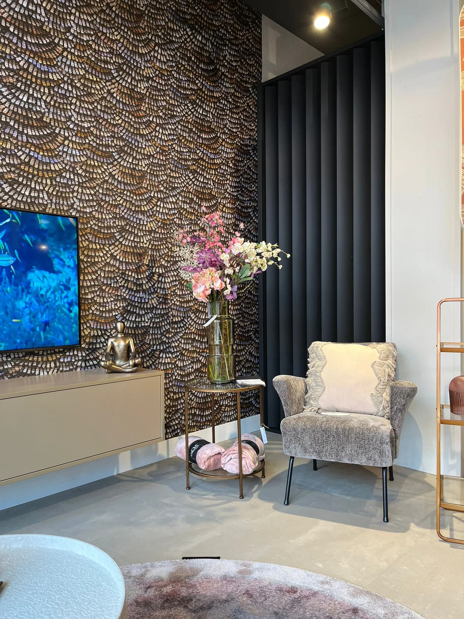 Fauteuil en bloemen voor een wand met verenbehang